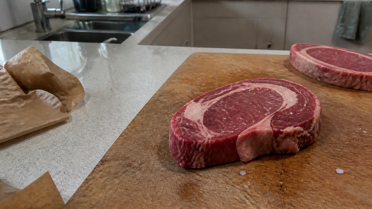 Two raw Australian beef steaks on a wooden chopping board in a home kitchen
