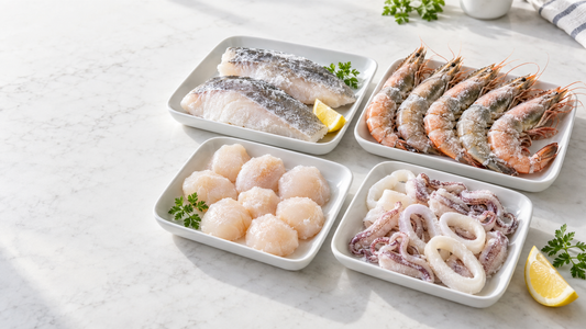Bright assortment of frozen fish fillets, prawns, scallops, and squid in separate trays