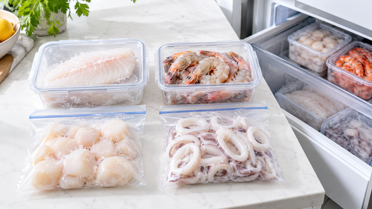 Bright organised frozen seafood portions in clear containers and freezer bags beside an open freezer